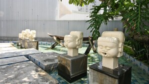 A tiled courtyard with stone sculptures and a metal fence. - Refinement Motel (Taichung)