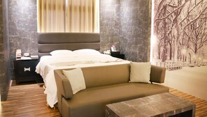A modern hotel room with a large bed, a sofa, a nightstand, and a wall mural. - Refinement Motel (Taichung)