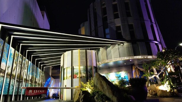A modern building with a sign in Chinese characters, a covered entrance area with a sign reading "EXIT", and a large rock feature in the foreground. - Refinement Motel (Taichung)