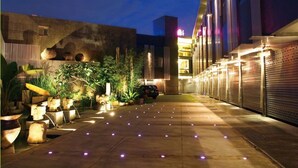 An outdoor area with a paved walkway, potted plants, and a parked car. - Refinement Motel (Taichung)