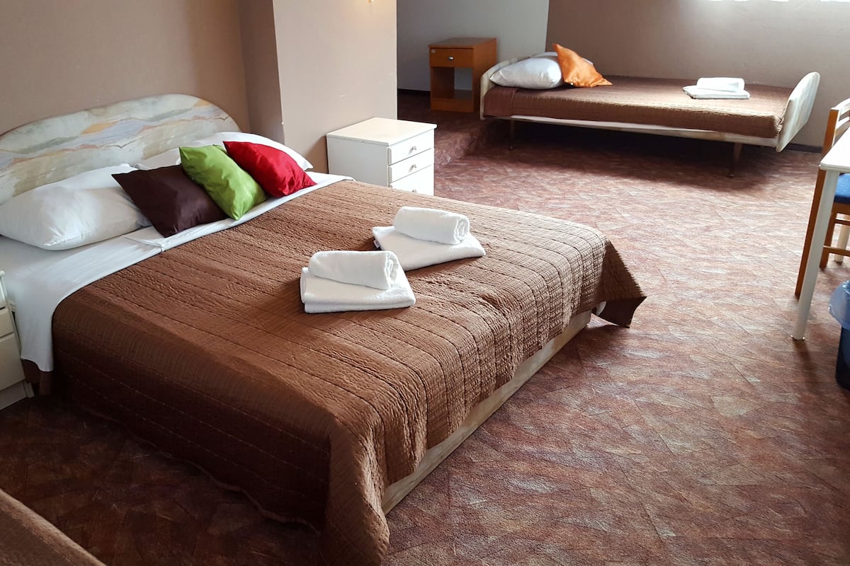 A hotel room with a large bed, a bedside table, a nightstand, a chair, and a desk.
