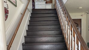 A wooden staircase with a handrail, leading to a landing with a mirror and a wooden barrel. - Foster Lake Inn (Sweet Home)