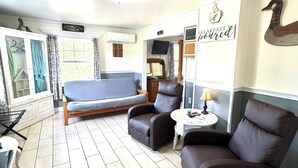 A room with a bed, two armchairs, a small table, a TV, and a 'Welcome' sign. - Foster Lake Inn (Sweet Home)