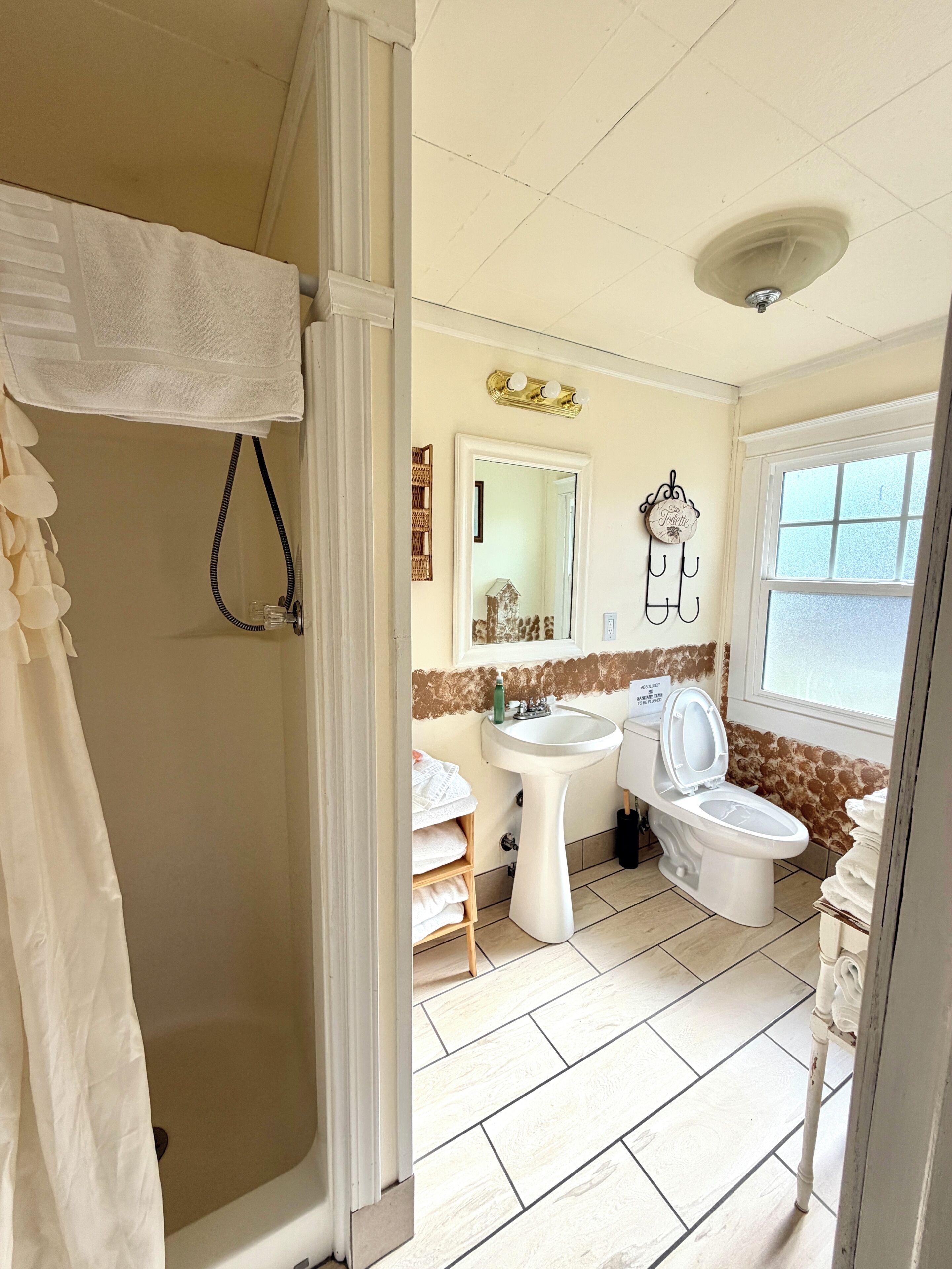 A bathroom with a shower, sink, toilet, and a mirror.