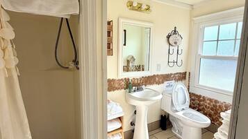 A bathroom with a shower, sink, toilet, and a mirror.