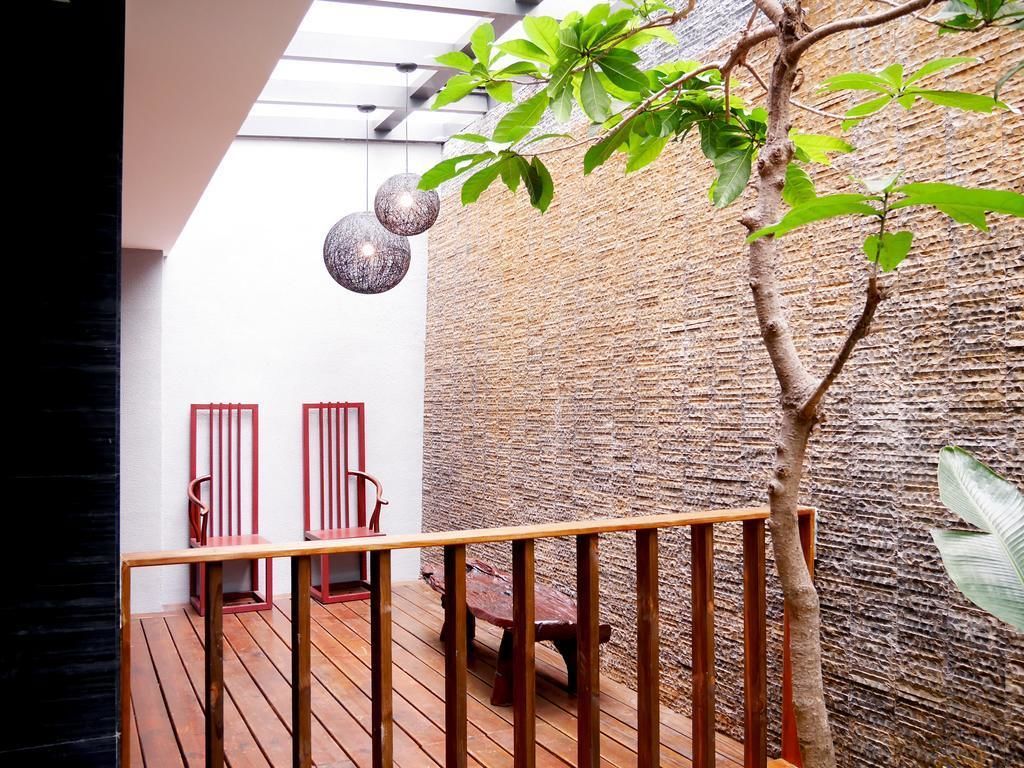 A wooden deck with a railing, a tree, and a textured wall.