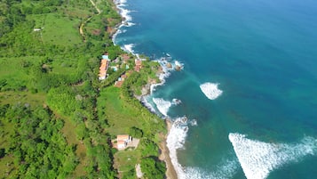 An aerial view of a coastal area with a mix of greenery and buildings along the shoreline.