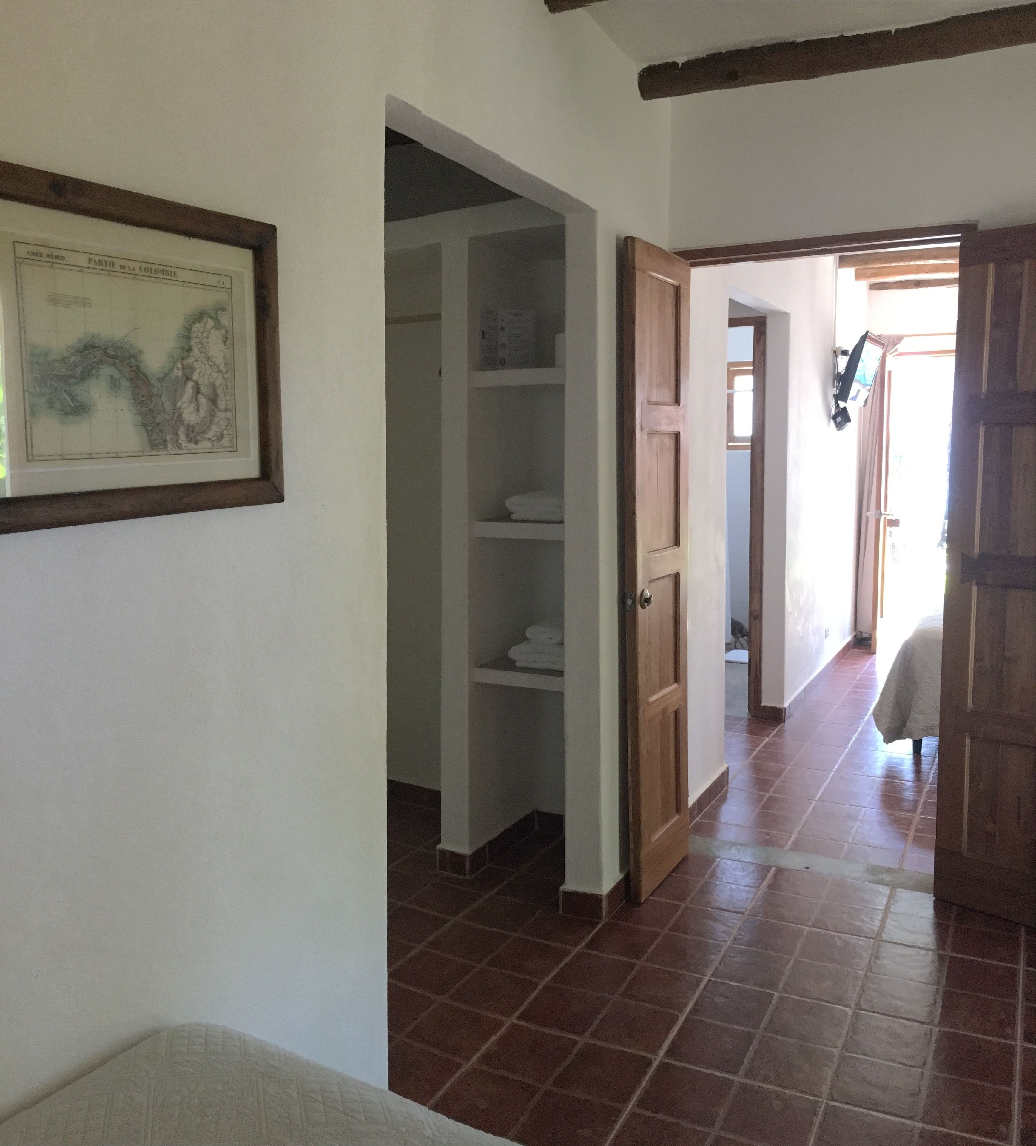 A hallway with a tiled floor, a wooden door, and a framed picture on the wall.