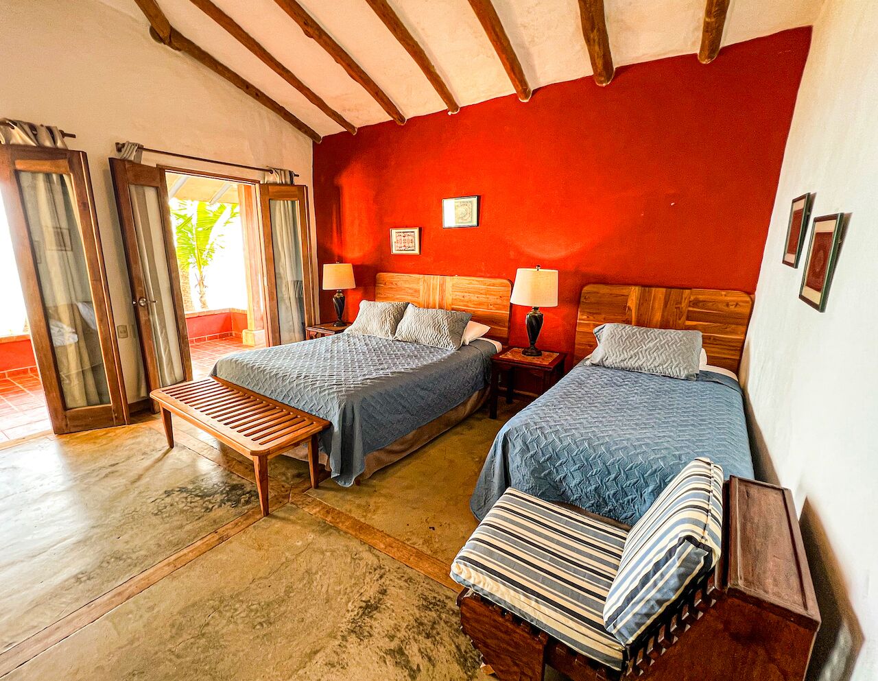 A room with two beds, wooden benches, and a bench with striped cushions.