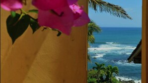 A view through an archway with pink flowers, overlooking a beach with palm trees and a thatched-roof structure. - Hotel Punta Franca (Punta Mala)