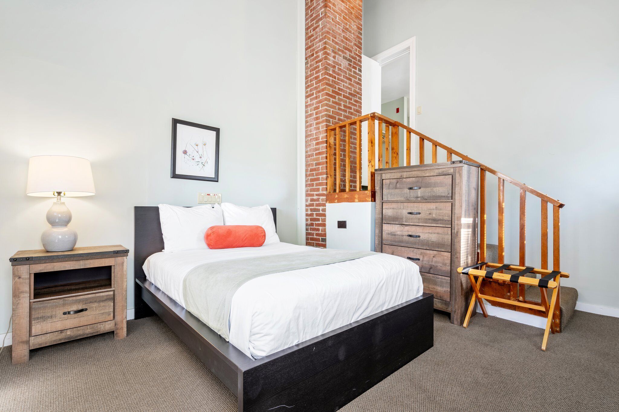Un dormitorio con cama, mesita de noche, cómoda y una silla de madera.