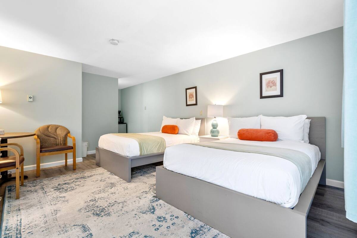 A hotel room with two beds, a desk, and a chair.