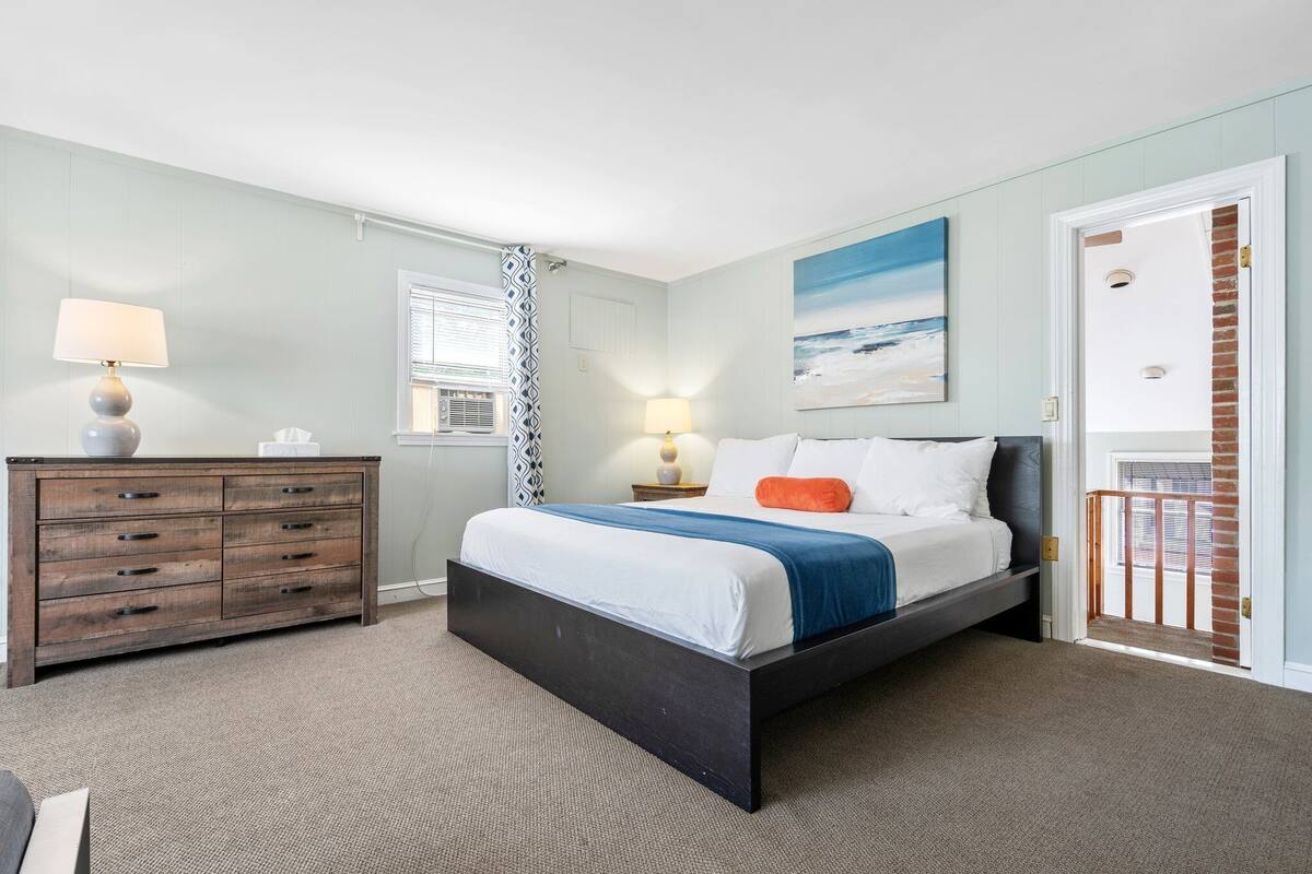 A bedroom with a bed, dresser, and a painting on the wall.