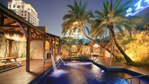 A pool area with a wooden deck, palm trees, and a building in the background. - Lanxia Boutique Motel (Taichung)