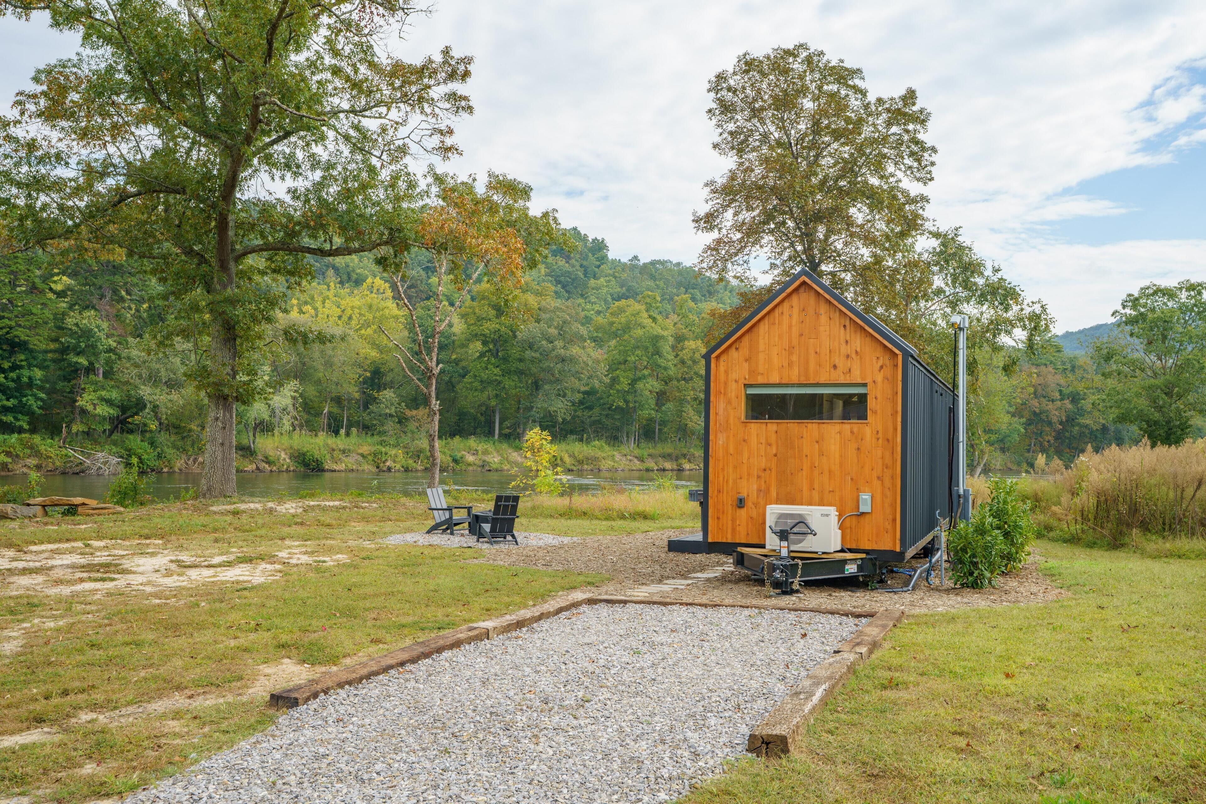 A cabin with a wooden exterior, a gravel area, and a view of a forested area.