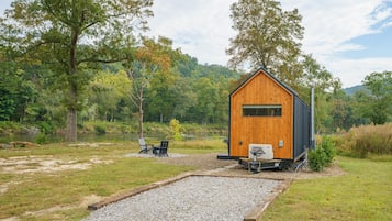 A cabin with a wooden exterior, a gravel area, and a view of a forested area.