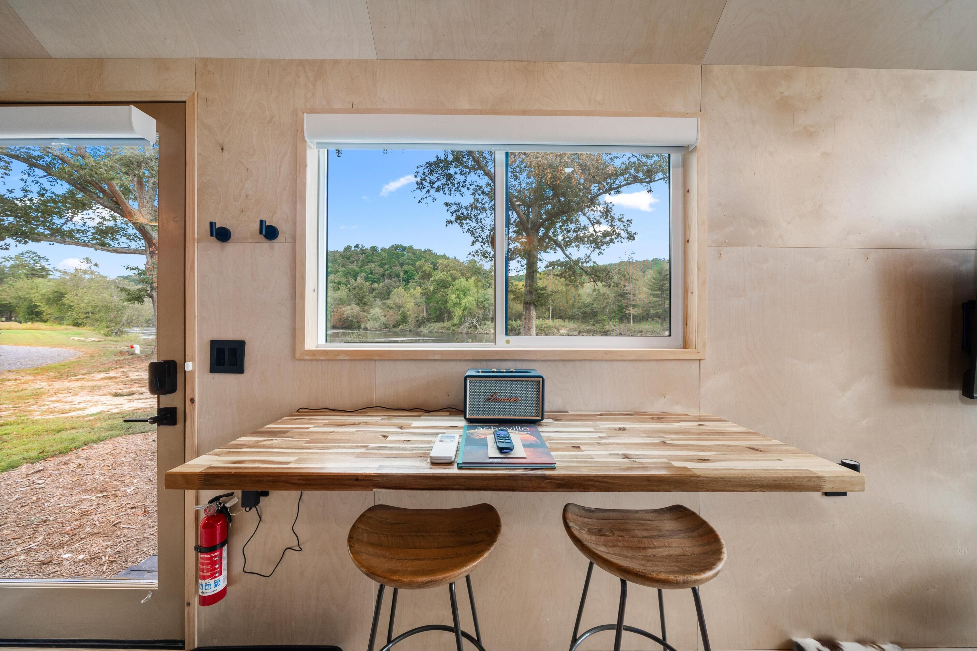 Un interior de madera con una ventana, una radio y dos taburetes.