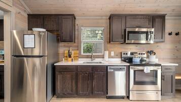 Une cuisine moderne dotée d’appareils électroménagers en acier inoxydable, de meubles en bois et d’une fenêtre avec des stores.