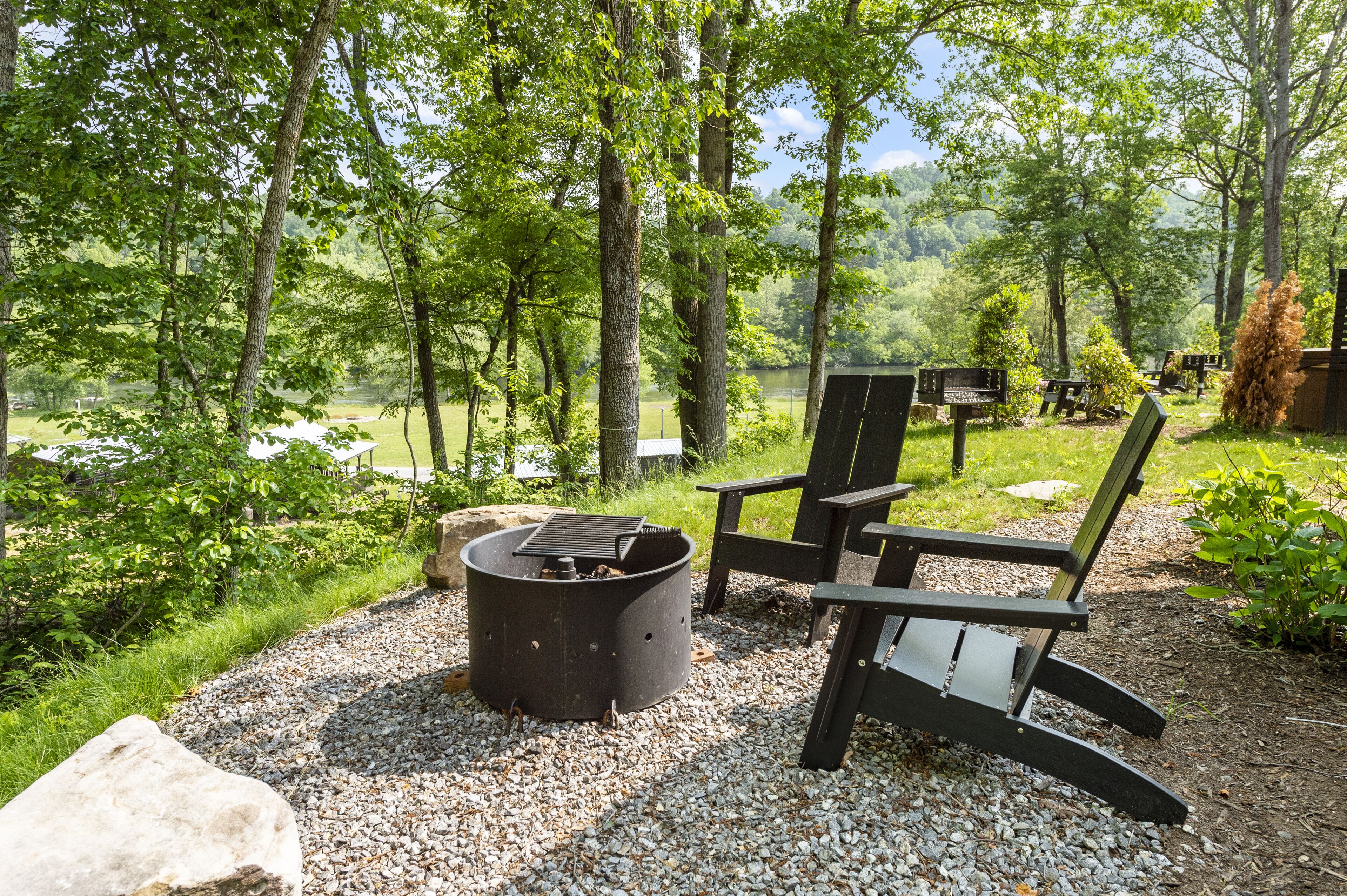 Un espace boisé équipé d’un foyer et de chaises Adirondack.