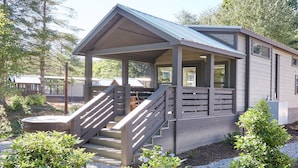 Een chalet met een veranda, houten trappen en een overdekt terras.