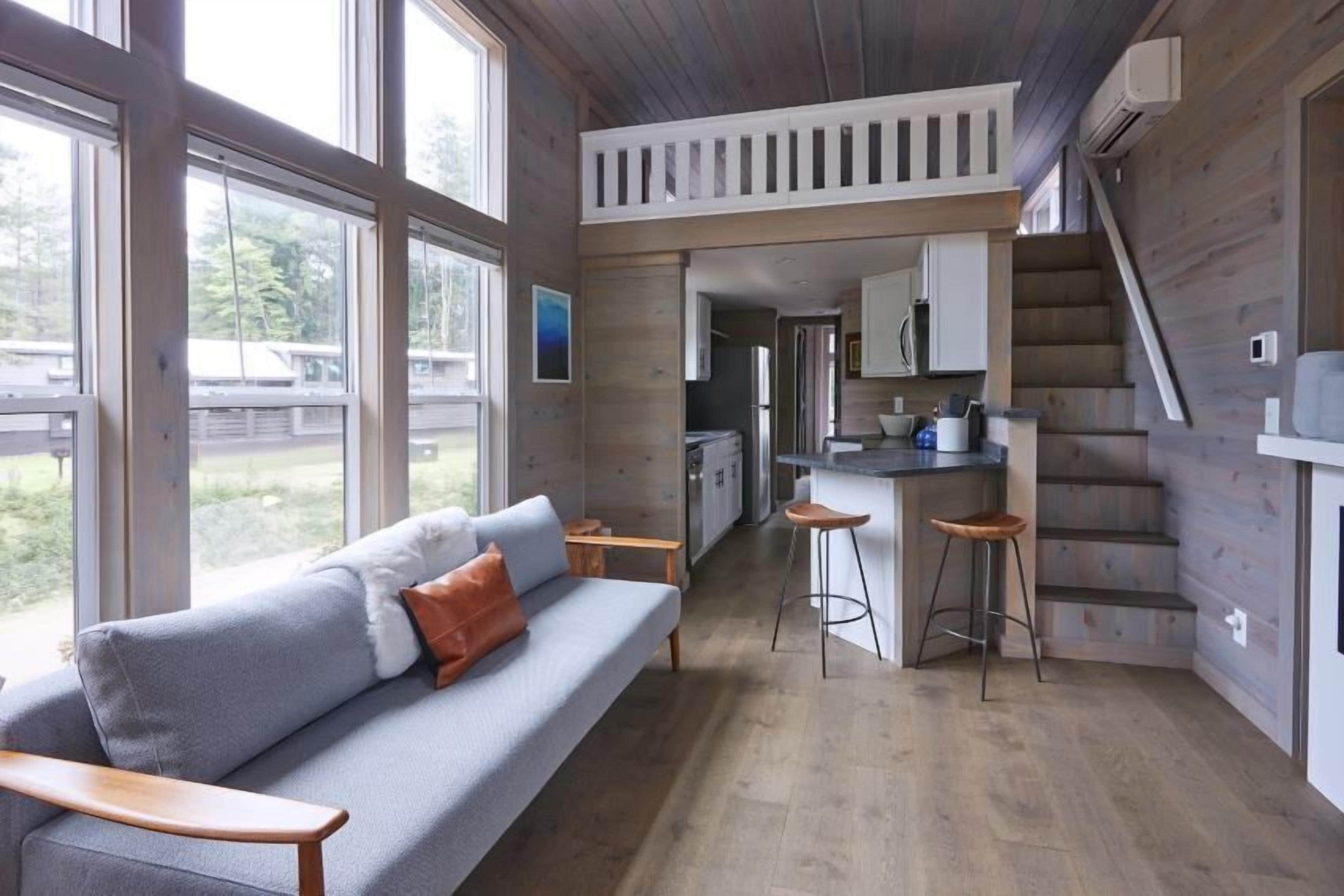 Espacio habitable pequeño con sofá, zona de cocina y una escalera.