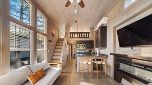 Een moderne keuken met een grote televisie, houten vloeren en een gezellige zithoek met een bank en stoelen.