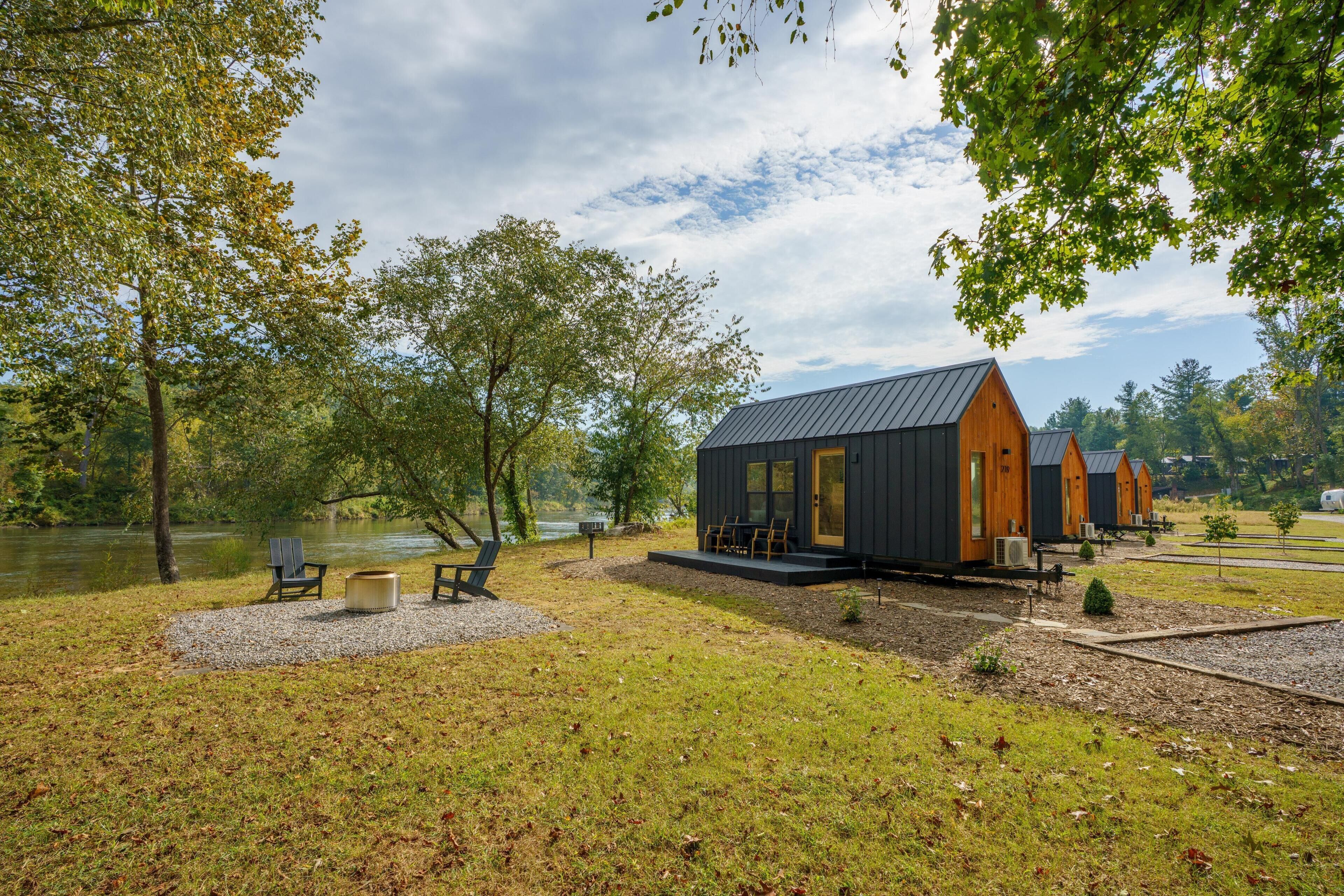 Una cabaña junto al lago con terraza, asientos al aire libre y vistas al lago.
