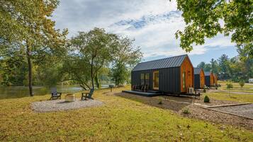 Una cabaña junto al lago con terraza, asientos al aire libre y vistas al lago.