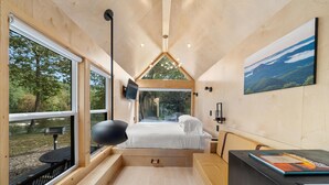Een moderne, compacte kamer met een bed, bureau en groot raam met uitzicht op de omgeving.