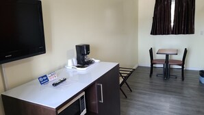 A small hotel room with a TV, a coffee maker, a remote control, and a sign prohibiting smoking. - Norvic Motel (Sudbury)