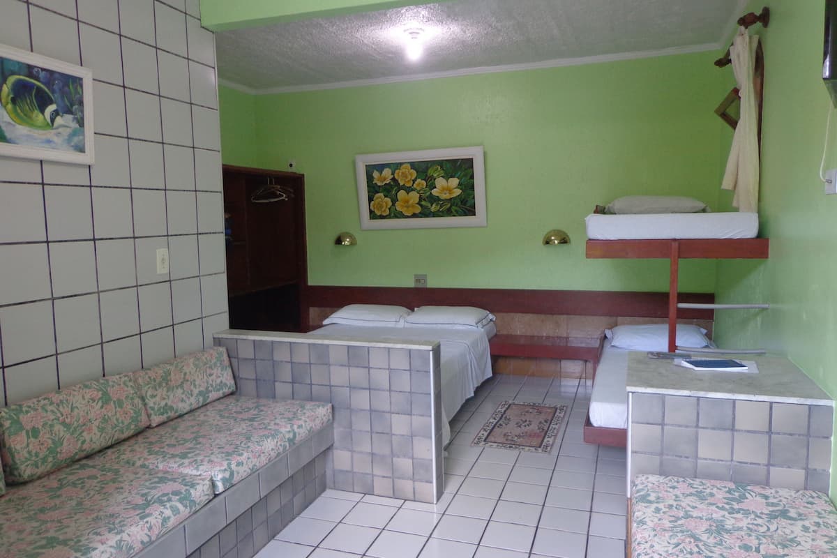 A room with a bunk bed, a sofa, a small table, and a painting on the wall.
