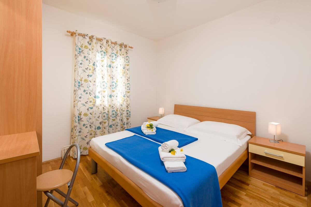 Habitación de hotel ordenada con una cama, mesita de noche y una silla.