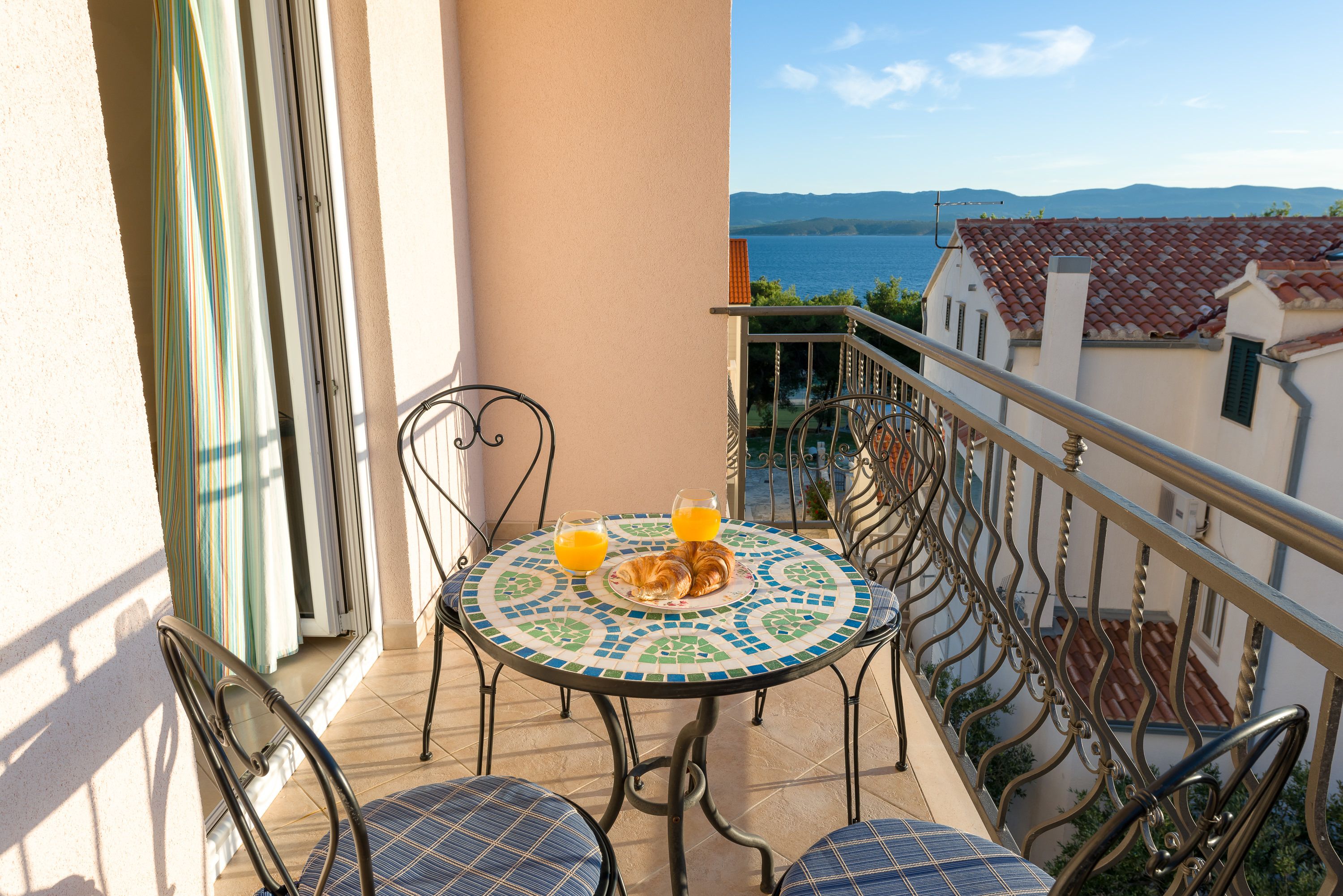 Ein Balkon mit einem gefliesten Tisch, zwei Stühlen und Meerblick.