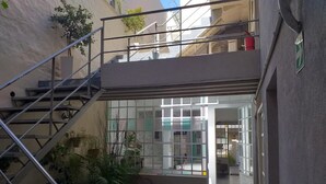 A multi-level building with a staircase leading to an upper floor. There are potted plants and a chair near the entrance. - Boho Rooms (Buenos Aires)