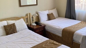 A hotel room with two beds, a bedside table with a lamp, a phone, and a mirror on the wall. - Hotel Mediterráneo Plaza (San Salvador)