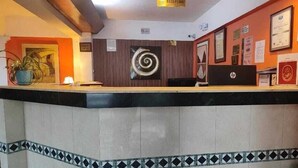 A reception area with a counter, a sign indicating the reception, and various certificates and awards on the wall. - Hotel Mediterráneo Plaza (San Salvador)