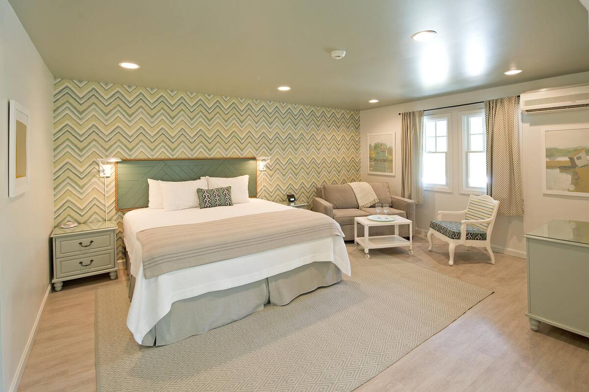 A bedroom with a bed, nightstands, a chair, a small table, and a dresser.