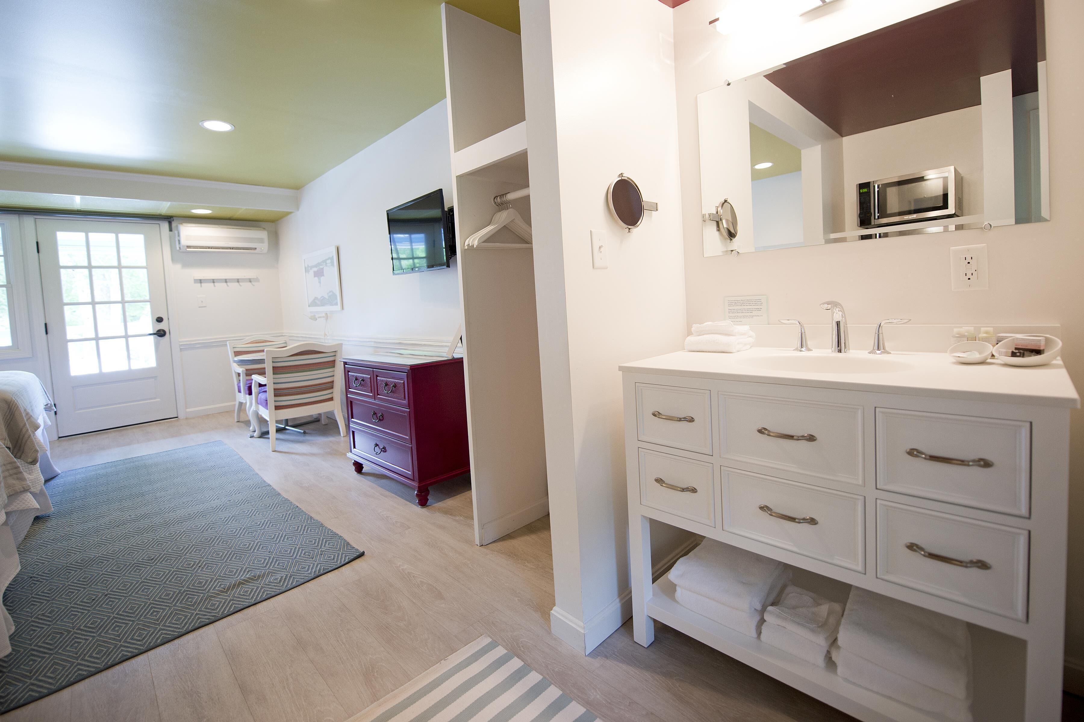A modern bathroom with a white vanity, a large mirror, and a built-in microwave.