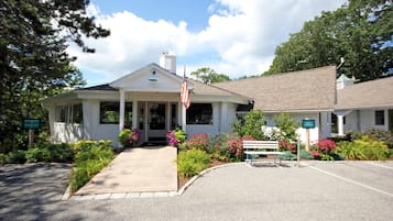 A two-story building with a white exterior, a front porch, and a flag.