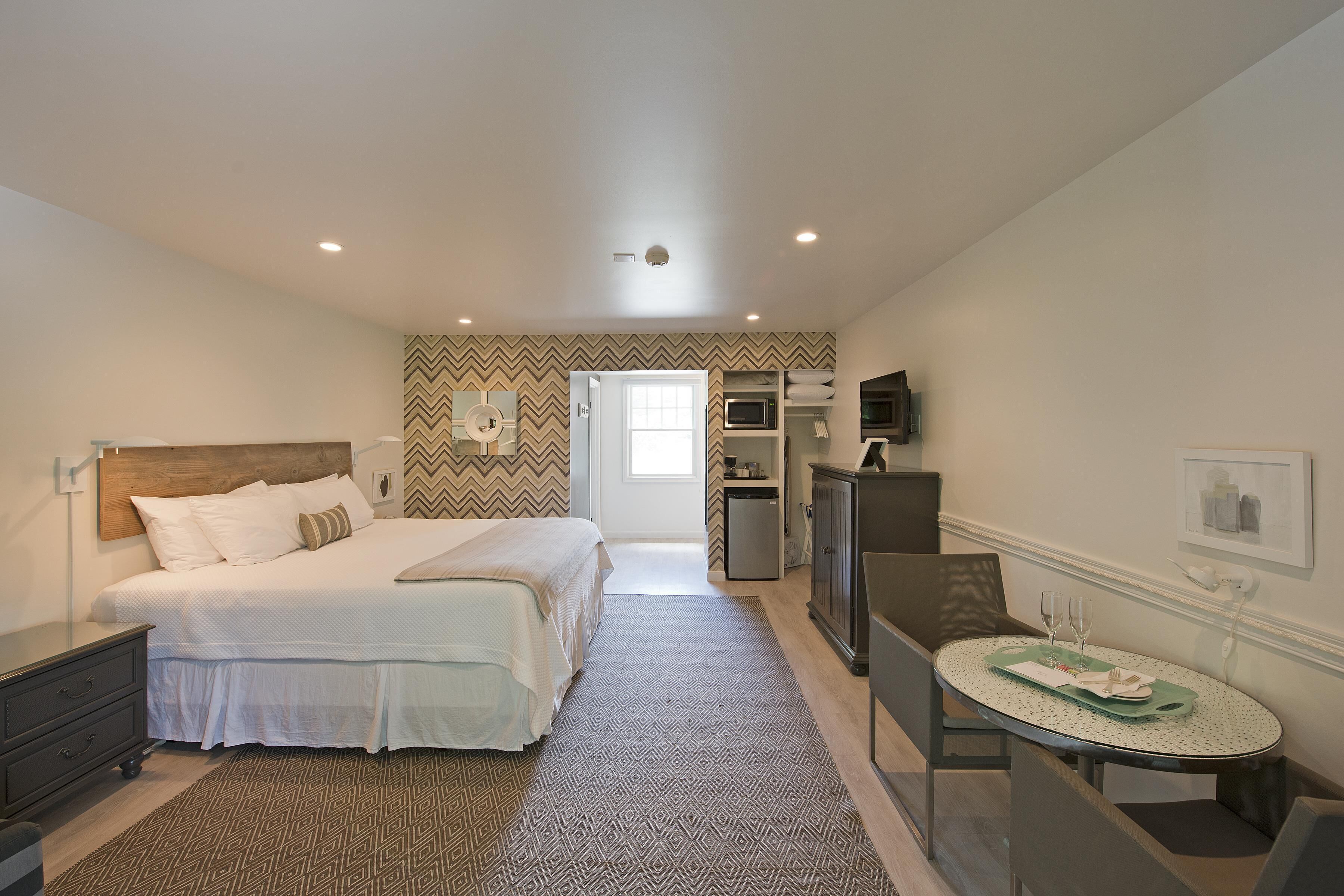 Une chambre à coucher comprenant un lit, une table de chevet, une commode et une petite table à manger avec un plateau.