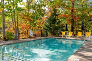 Una piscina al aire libre de temporada, sombrillas