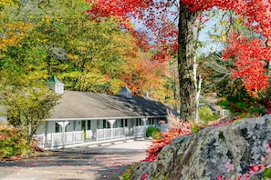 A white building with a green roof, a porch with white railings, and a stone pathway leading to it. - The Lodge at the Cove (Kennebunkport)