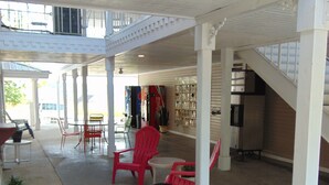 Un espacio al aire libre cubierto con una disposición de asientos que incluye sillas y mesas rojas, una escalera y un refrigerador de Coca-Cola.