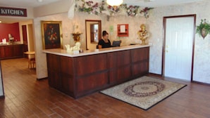 Una zona de recepción con un mostrador de madera, un cartel que indica la cocina y una puerta.