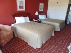 Habitación de hotel con dos camas, una silla y piso cubierto con alfombra roja.