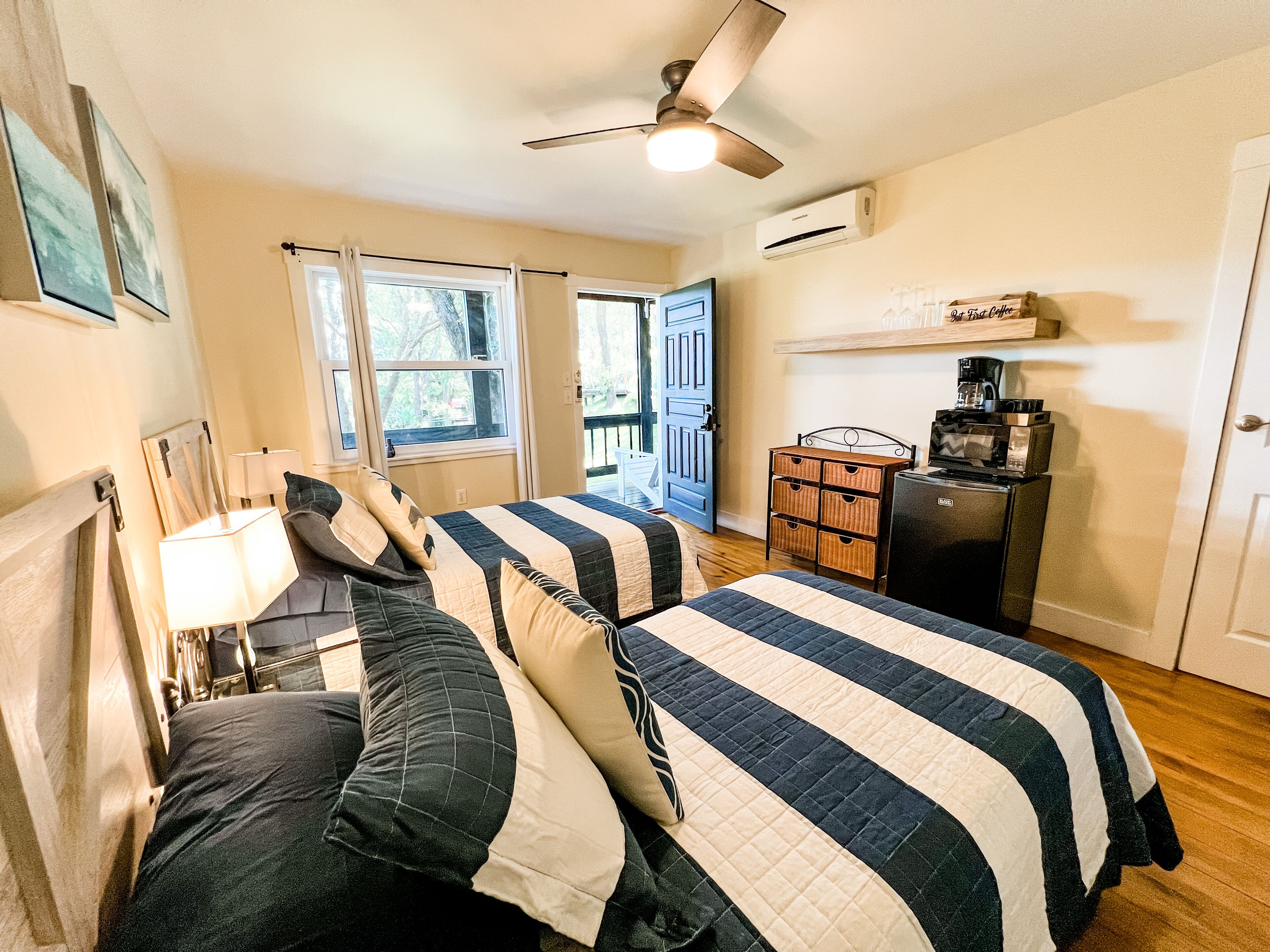 A bedroom with two beds, a ceiling fan, a dresser, and a coffee maker.