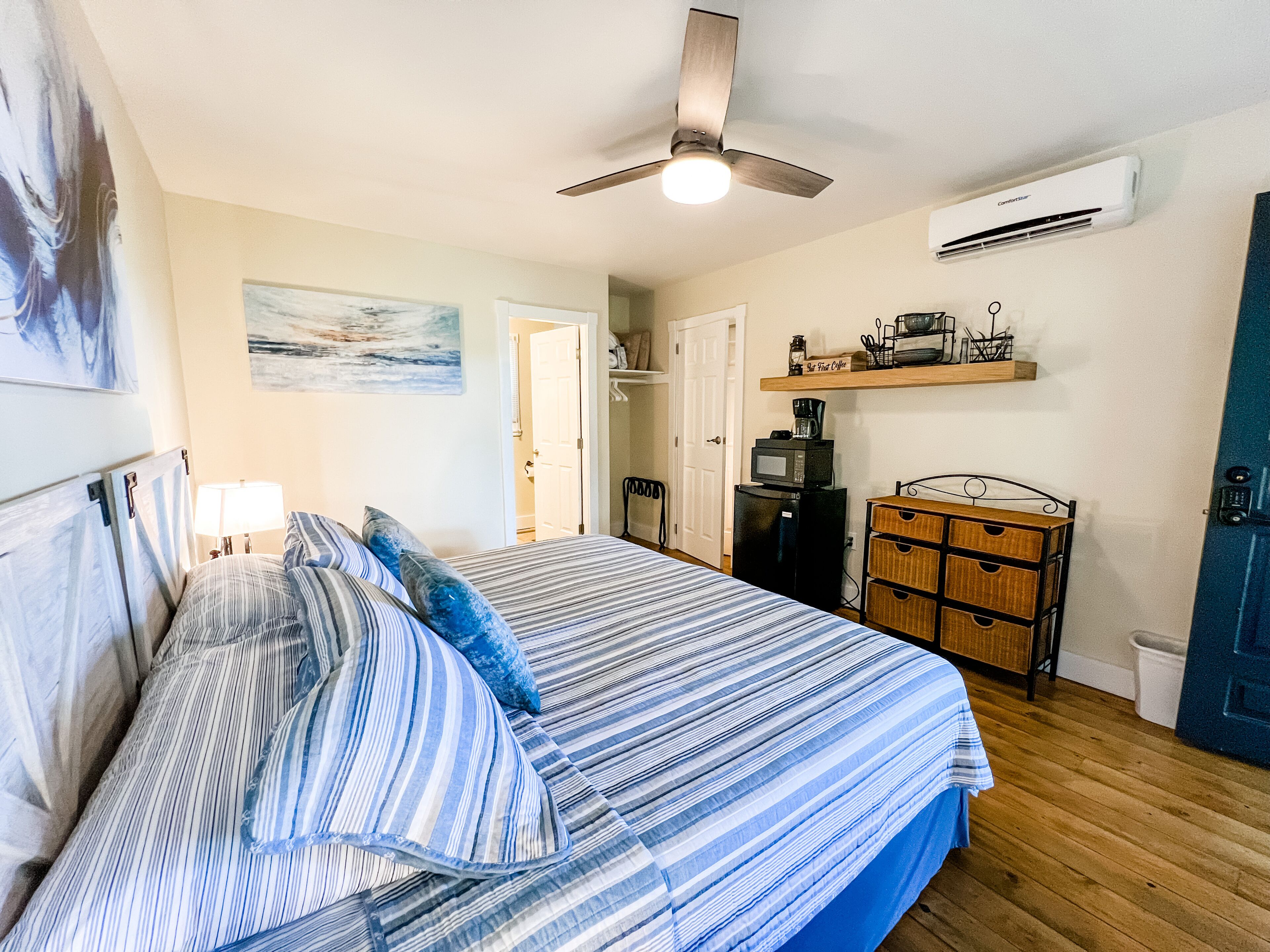 Une chambre à coucher comprenant un lit, un ventilateur de plafond, une machine à café et une commode.