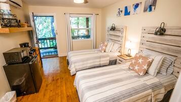 A bedroom with two beds, a refrigerator, a microwave, and a ceiling fan.