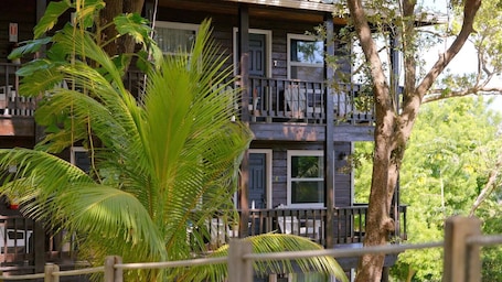 Un edificio de madera de varios pisos con balcones, rodeado de abundante vegetación.