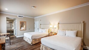 A hotel room with two beds, a desk, a chair, a mirror, and a bathroom visible through an open door.